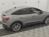 the rear end of a gray car parked in a garage