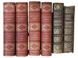 several old books are lined up in a row on a white surface