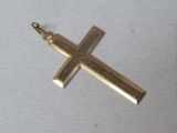 a gold cross that is laying on a white surface