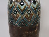 a brown and blue vase sitting on a white surface