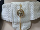 a close up of a white shirt with a gold broocher on it