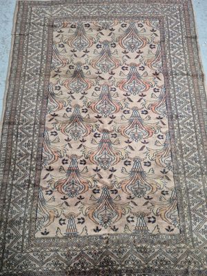 an antique persian rug with a floral design on a beige ground