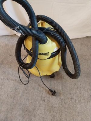 un aspirateur jaune muni d'un tuyau noir posé par terre