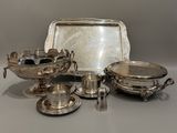 des assiettes et des plateaux en métal argenté posés sur une table avec des couverts en argent