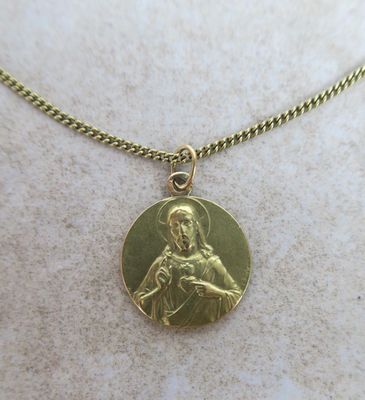 a close up of a gold plated necklace with an image of the virgin and child
