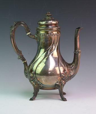 a silver tea pot on a stand on a table