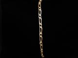 a gold bracelet with a link on a black background