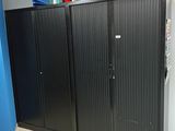 une armoire noire dans un coin d'une pièce, avec des livres posés dessus