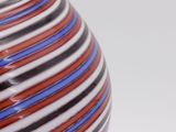 a striped vase sitting on a table with a white background