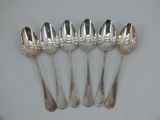six silver spoons are lined up on a white surface