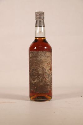 une vieille bouteille de whisky posée sur une table blanche