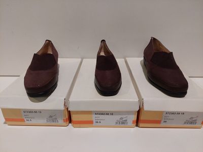 trois paires de chaussures marron posées sur des cartons, sur une surface blanche