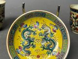 two cups and a plate with a dragon on them on a table