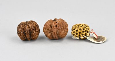 trois noix et une coquille de noix sur une surface blanche