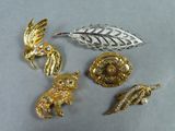 trois broches en or et en argent et une broche en forme de feuille