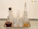 quatre bouteilles d'alcool posées sur un plateau en argent, sur une table