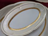 trois assiettes ornées de bordures dorées, posées sur une table rouge
