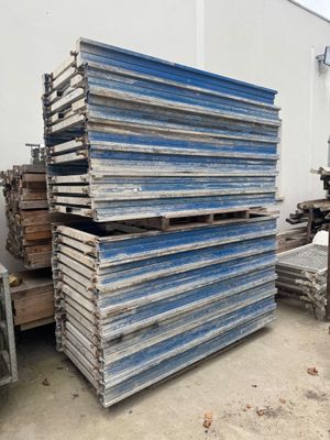plusieurs piles de bois empilées les unes sur les autres devant un bâtiment