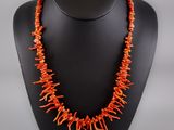 a necklace made of orange coral beads on a black mannequin