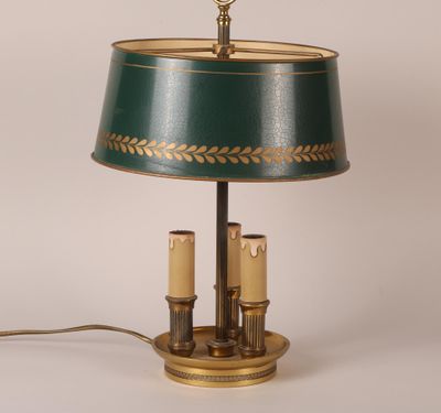 une lampe de table verte et dorée sur laquelle sont posées deux bougies