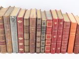 several old books are lined up in a row on a white surface