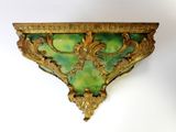 a green and gold wall shelf with a decorative design