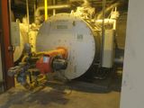 une photo d'une chaudière dans un bâtiment, avec des tuyaux et des vannes
