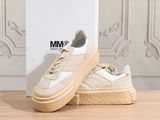 the white sneakers are on the wooden floor near the wall