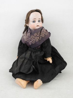 poupée assise par terre, vêtue d'une robe noire et d'un foulard