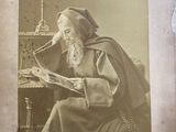 an old photo of a man sitting at a table reading a book