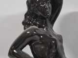 statue of a woman sitting on a rock with her hands on her hips