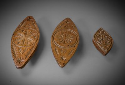 trois plaques en bois sculptées posées sur une surface grise