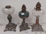 trois lampes anciennes en verre posées sur une table blanche