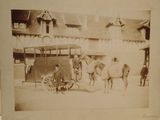 an old photo of a horse pulling a cart with a man standing next to it