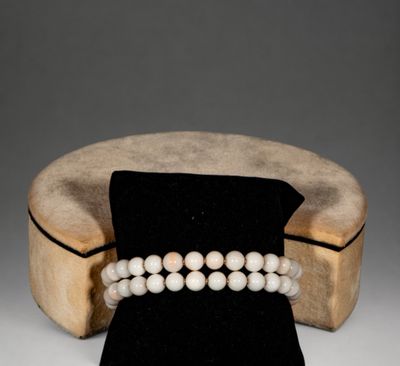 a close up of a bracelet with pearls on a wooden stand