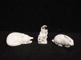 three figurines of animals sitting on a black surface