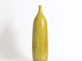 un vase jaune posé sur une surface blanche