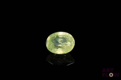 a close up of a green gemstone on a black surface