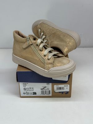 des baskets en cuir doré à lacets posées sur une boîte en carton