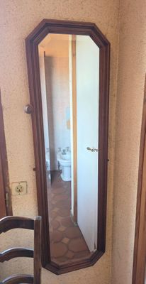 a mirror in the corner of a room with a chair in front of it