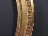 a close up of a gold oval mirror on a black wall