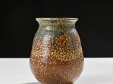 a brown and green vase sitting on a white table