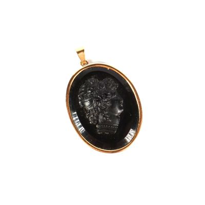 un gros plan sur un pendentif noir et doré représentant une tête de lion