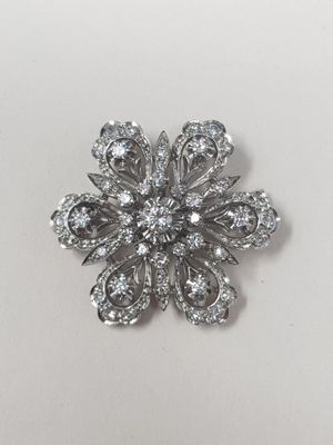un gros plan d'une broche en forme de fleur en diamant posée sur une surface blanche