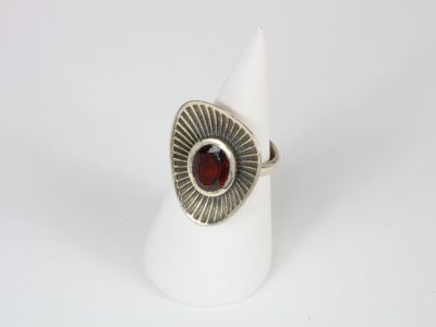a close up of a silver ring with a red stone in it