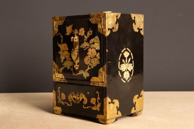 a black and gold cabinet with a flower design on it