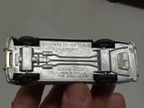 someone is holding a silver toy car in their hand