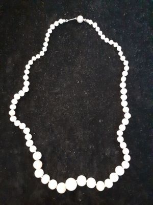 a close up of a necklace with white beads on a black surface