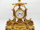 une horloge en or surmontée d'un oiseau