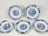 six assiettes bleues et blanches ornées de fleurs orange, posées sur une table